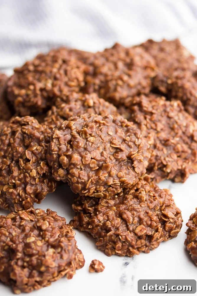Close up of a pile of vegan no bake cookies, showcasing their chewy texture and delicious chocolate-peanut butter coating.