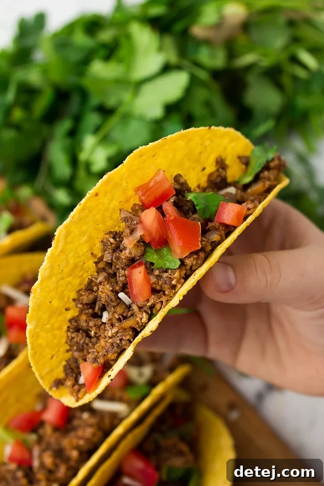 The Ultimate Vegan Taco Filling 3 hand holding a taco, lettuce in background