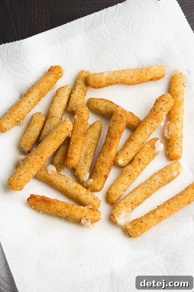 just fried vegan cheese sticks resting on paper towels to absorb excess oil