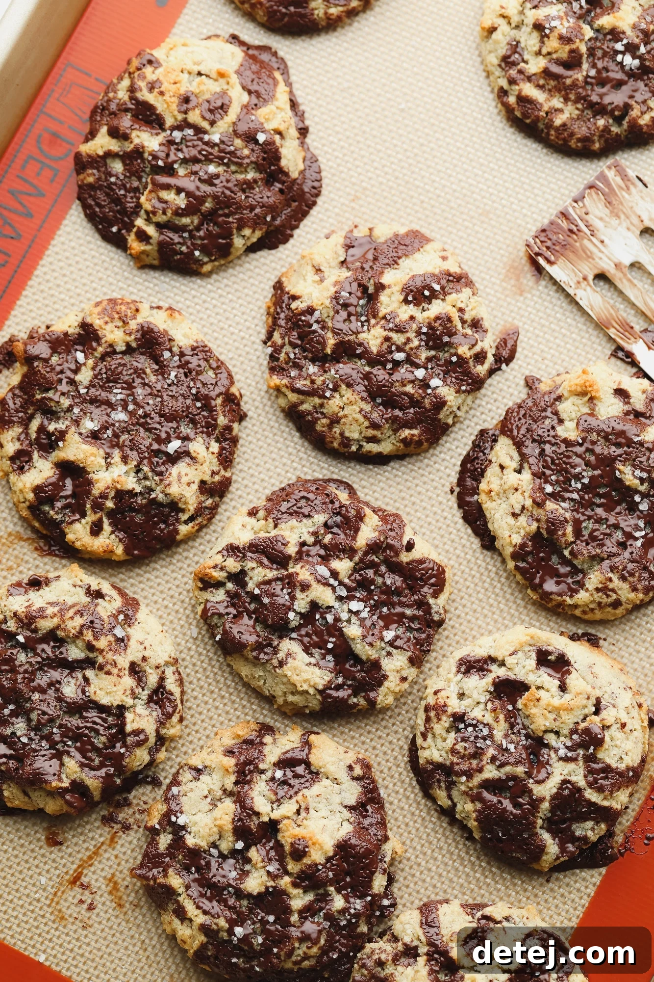 rows of baked almond flour chocolate chip cookies on a lined baking sheet.