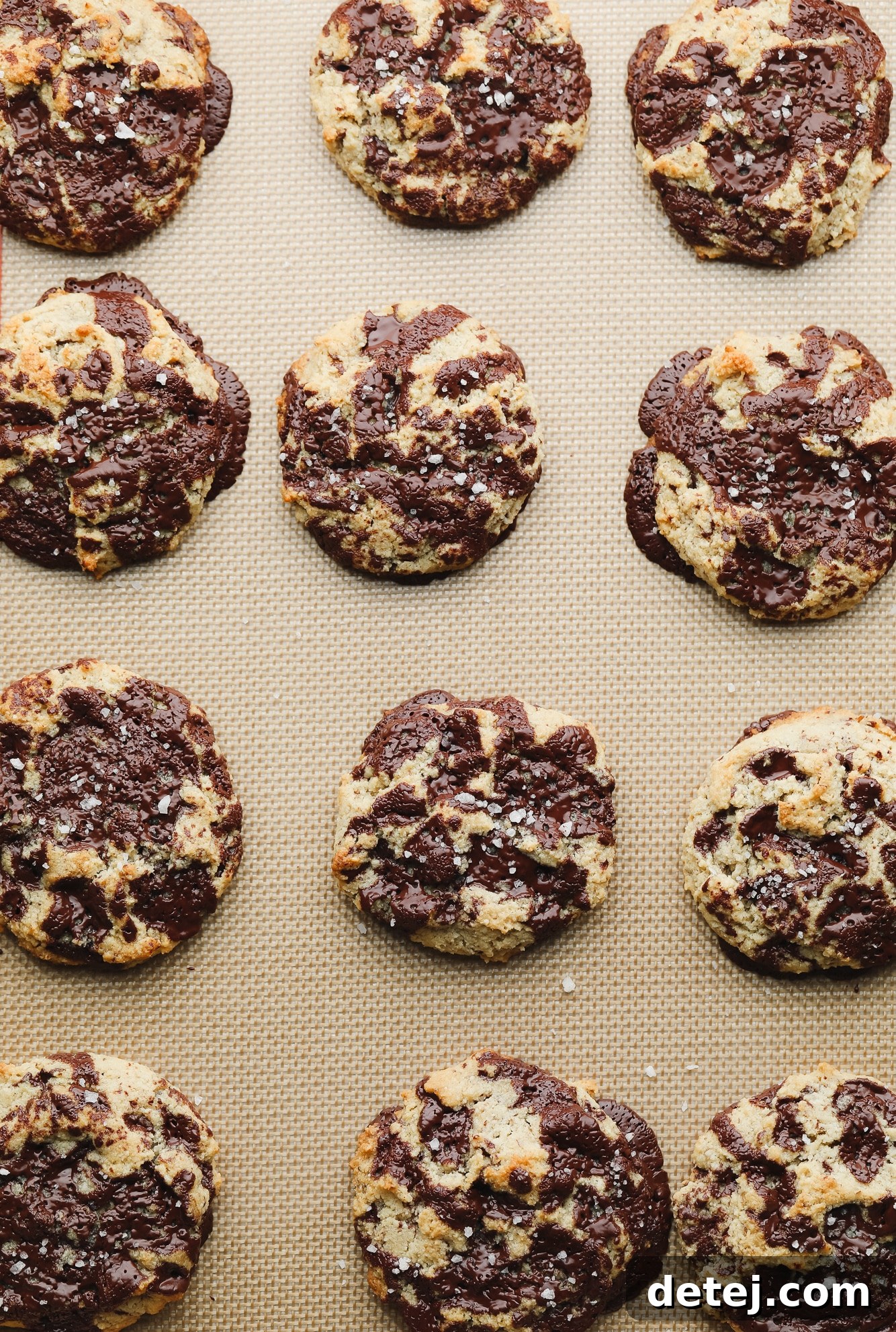 rows of baked almond flour chocolate chip cookies on a lined baking sheet.
