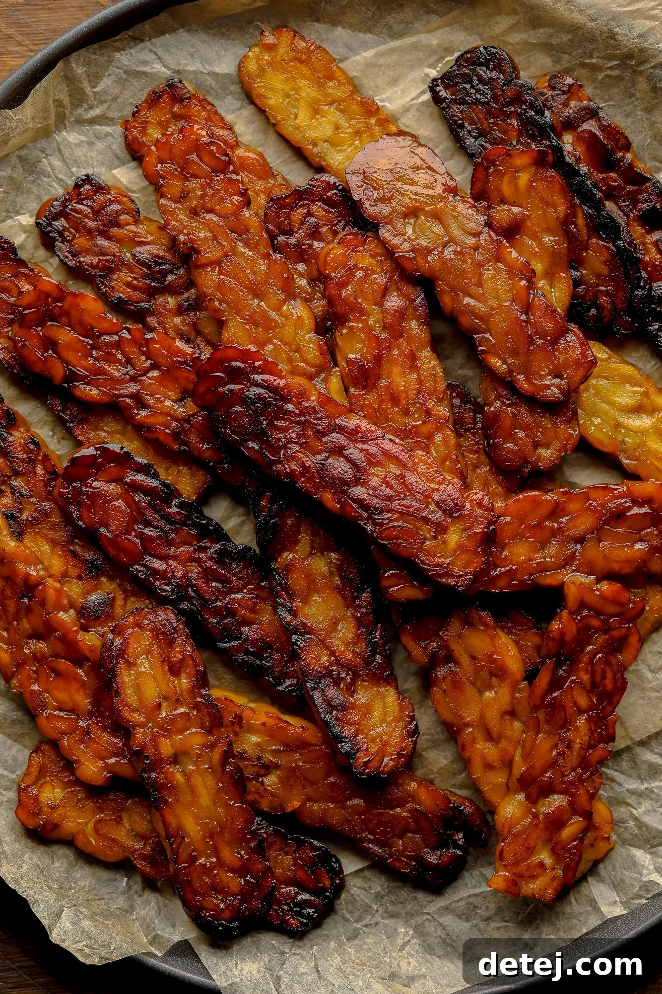 A close-up shot of crispy, pan-fried tempeh bacon slices, showcasing their golden-brown hue and irresistible texture.