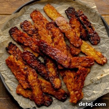 close up on a pile of pan-fried tempeh bacon slices.