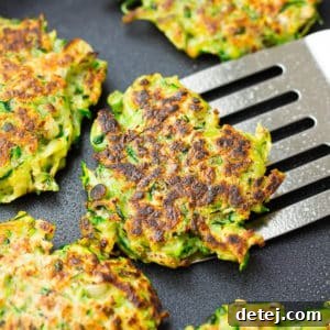 square image of a pan with fritters, one being lifted out with a spatula