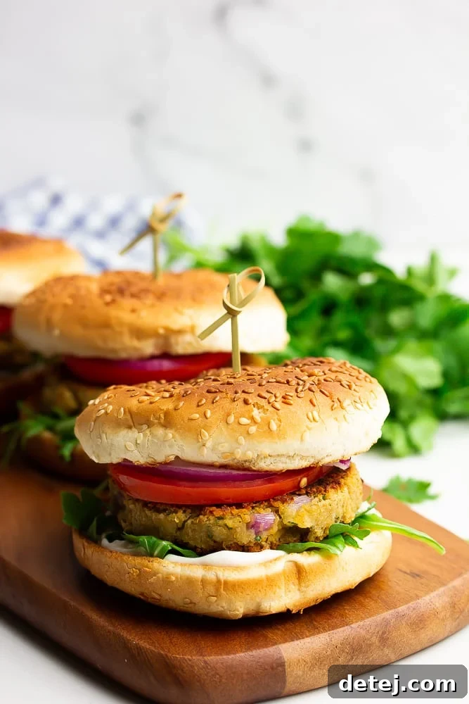 A perfectly styled row of three golden chickpea burgers on a rustic cutting board against a elegant white marble background, showcasing their delicious appeal.