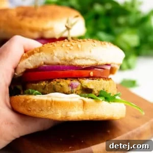 Square image of a delicious chickpea burger with a hand holding it