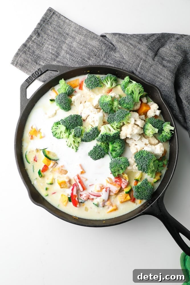 Vibrant Vegan Thai Green Curry 5 pan full of vegetables and coconut milk, fresh broccoli on top