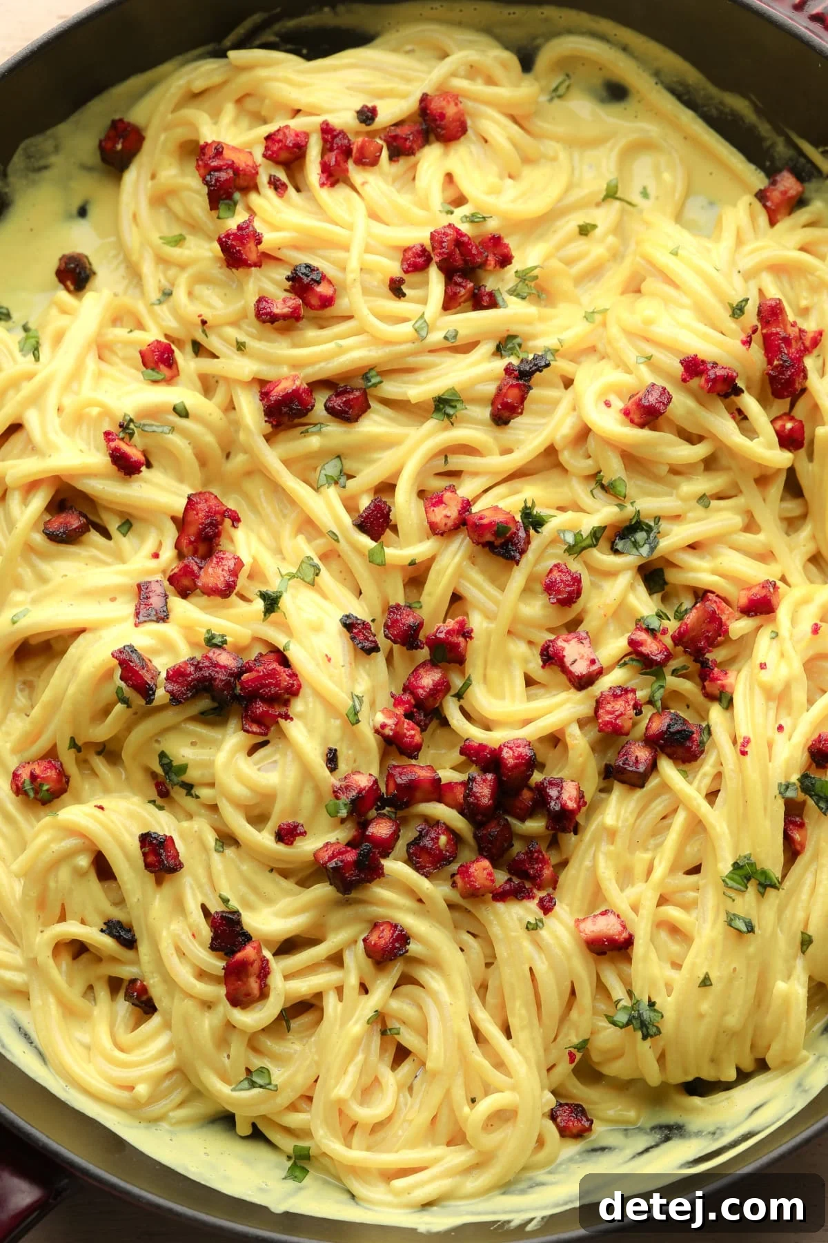 pan full of yellow spaghetti and reddish tofu pieces