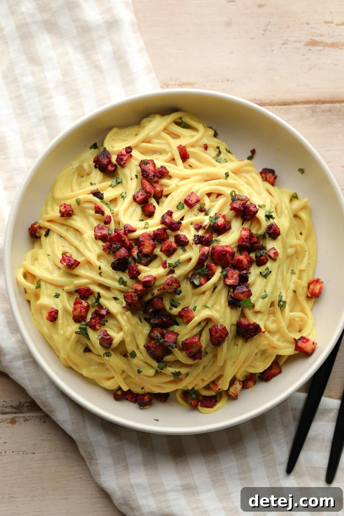 looking down on a bowl of vegan carbonara with tofu bits on wooden background