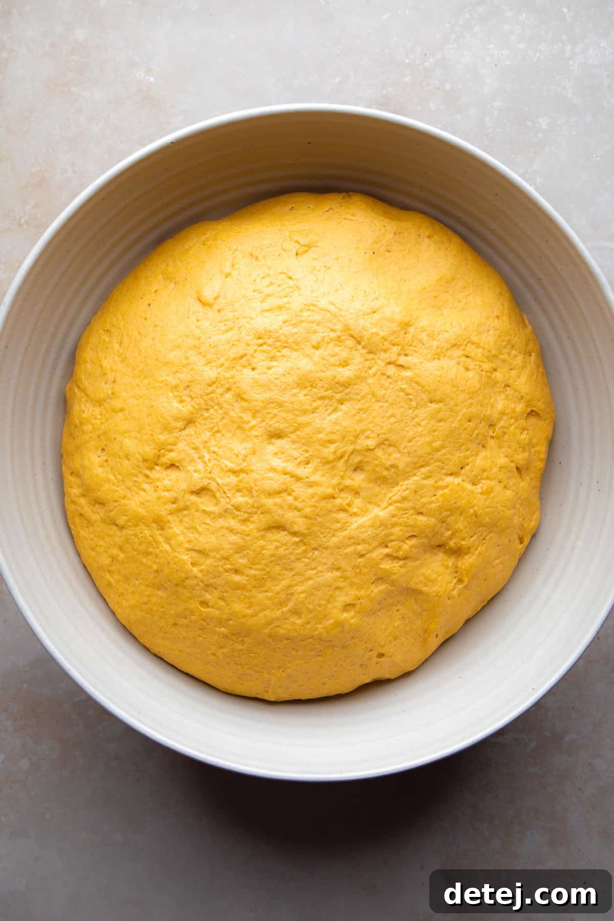 pumpkin cinnamon roll dough in bowl after rising