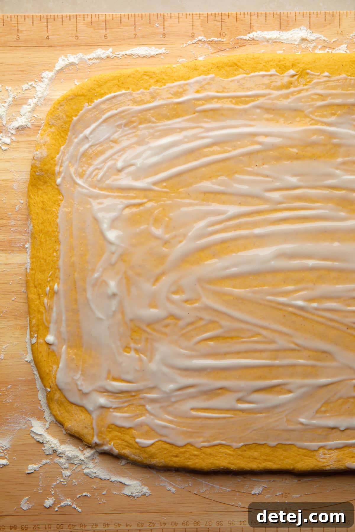 butter on pumpkin cinnamon roll dough before being rolled up