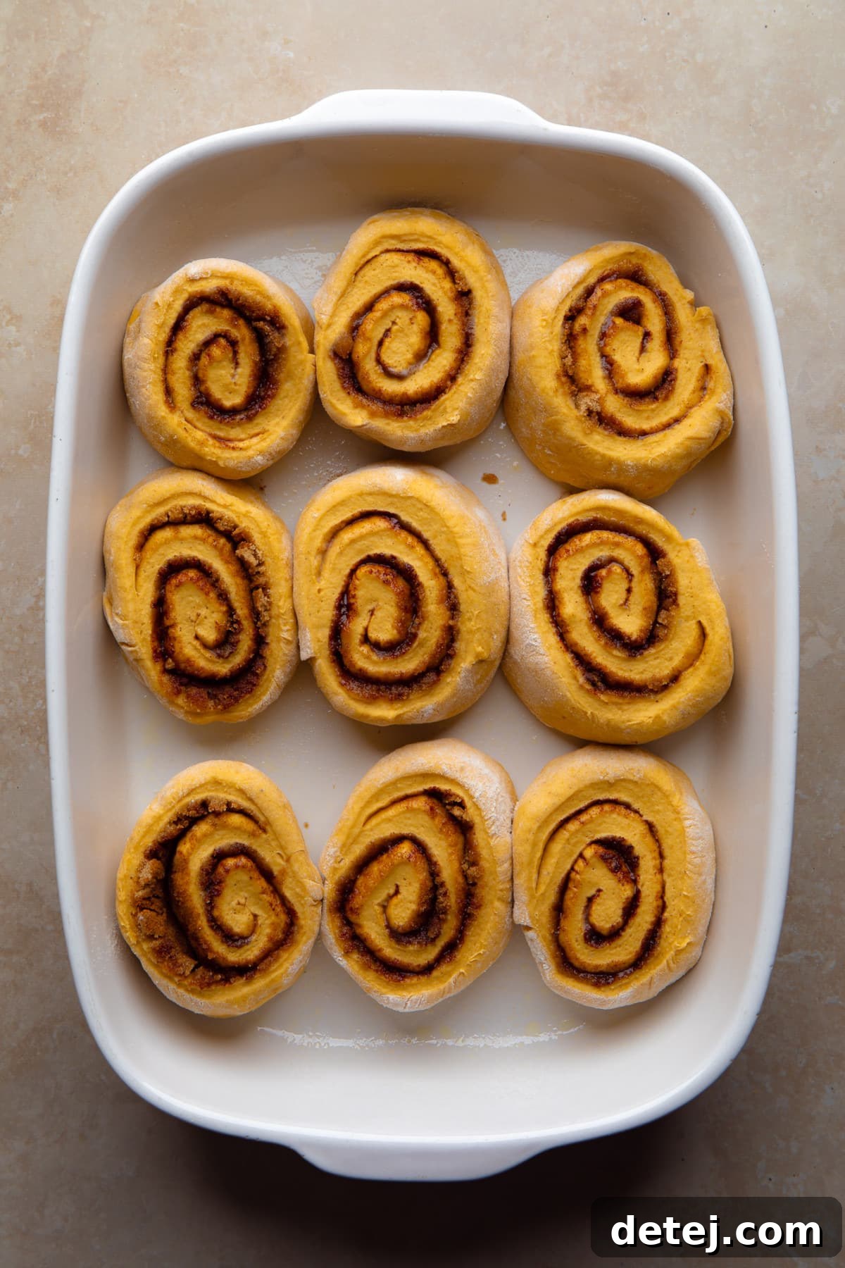 uncooked cinnamon rolls in a white dish