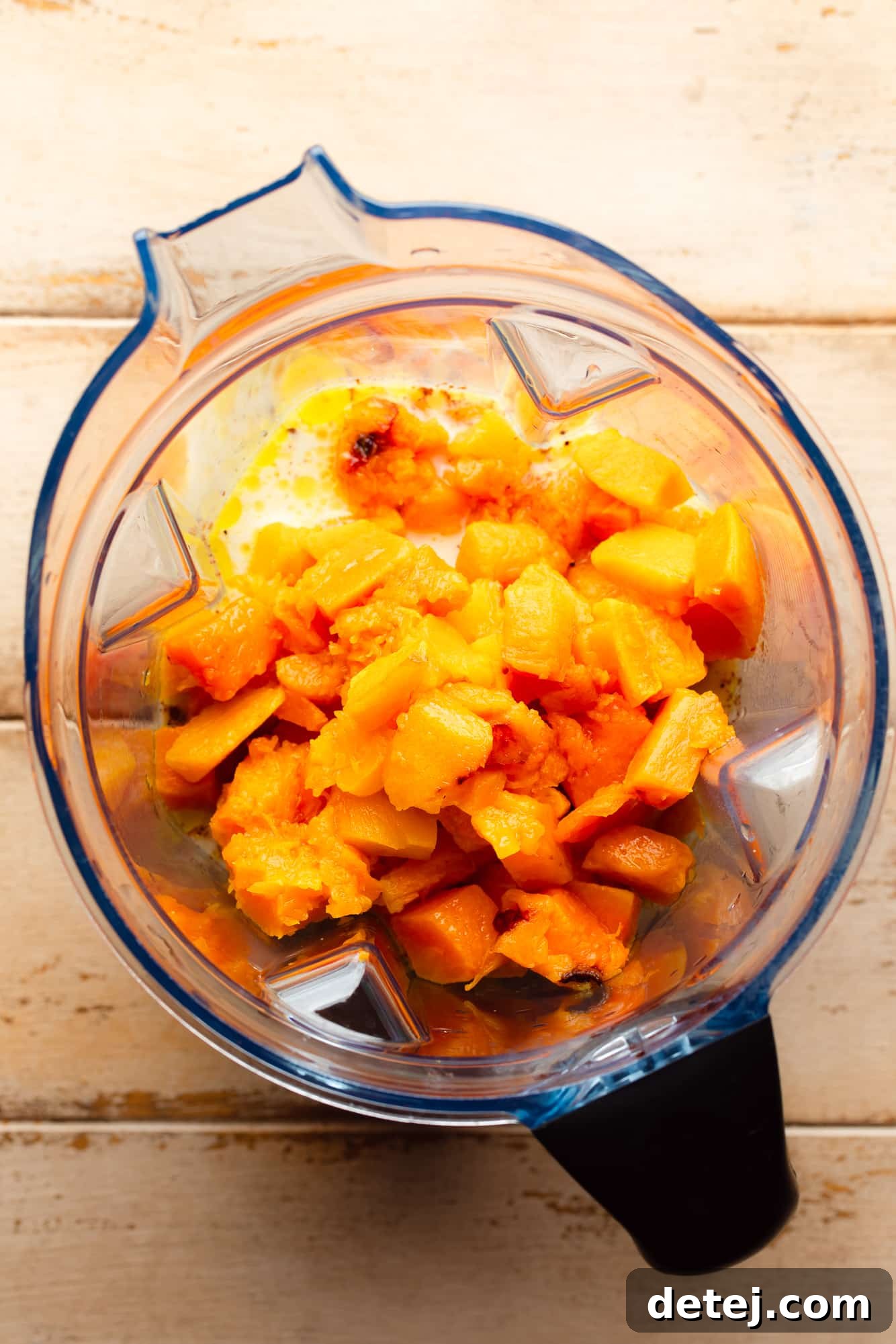 Roasted butternut squash cubes in a blender, ready to be processed into sauce.