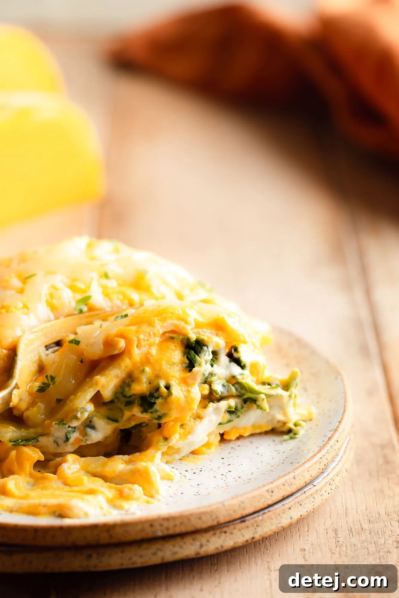 Close up on a fork cutting into a warm slice of vegan butternut squash lasagna on a plate, showing the creamy layers.