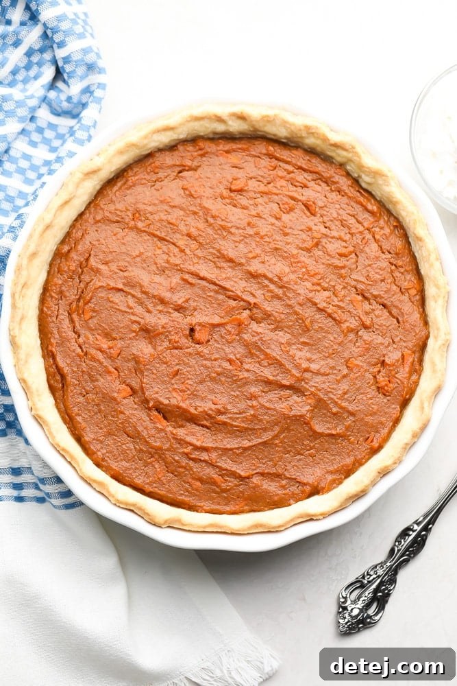 A full vegan sweet potato pie on a white surface with a rustic blue kitchen towel in the background