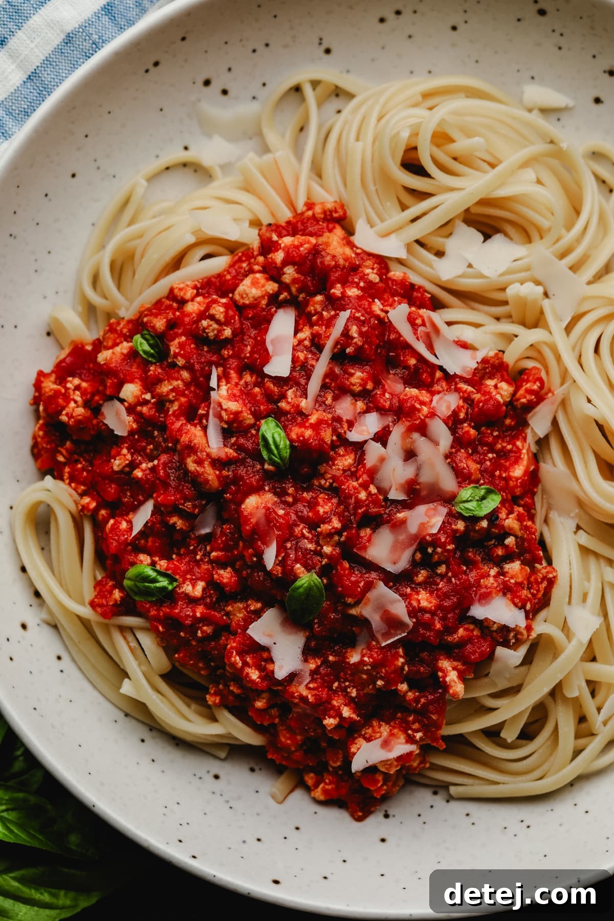 A top-down view of a bowl of spaghetti with rich red vegan bolognese sauce, featuring noticeable tofu crumbles for a meaty texture.
