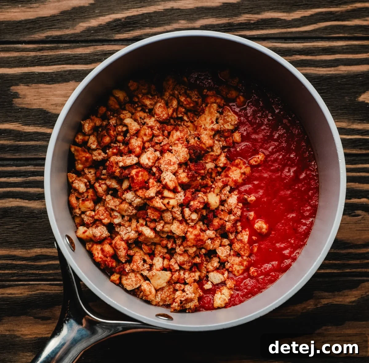 Small grey pan with warm marinara sauce mixed with cooked, brown tofu crumbles, forming the vegan bolognese.