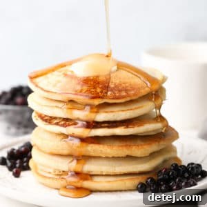 square image of pancake stack with syrup being poured, blueberries around them