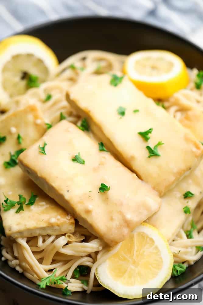 Crispy creamy lemon tofu served over pasta, garnished with fresh parsley.
