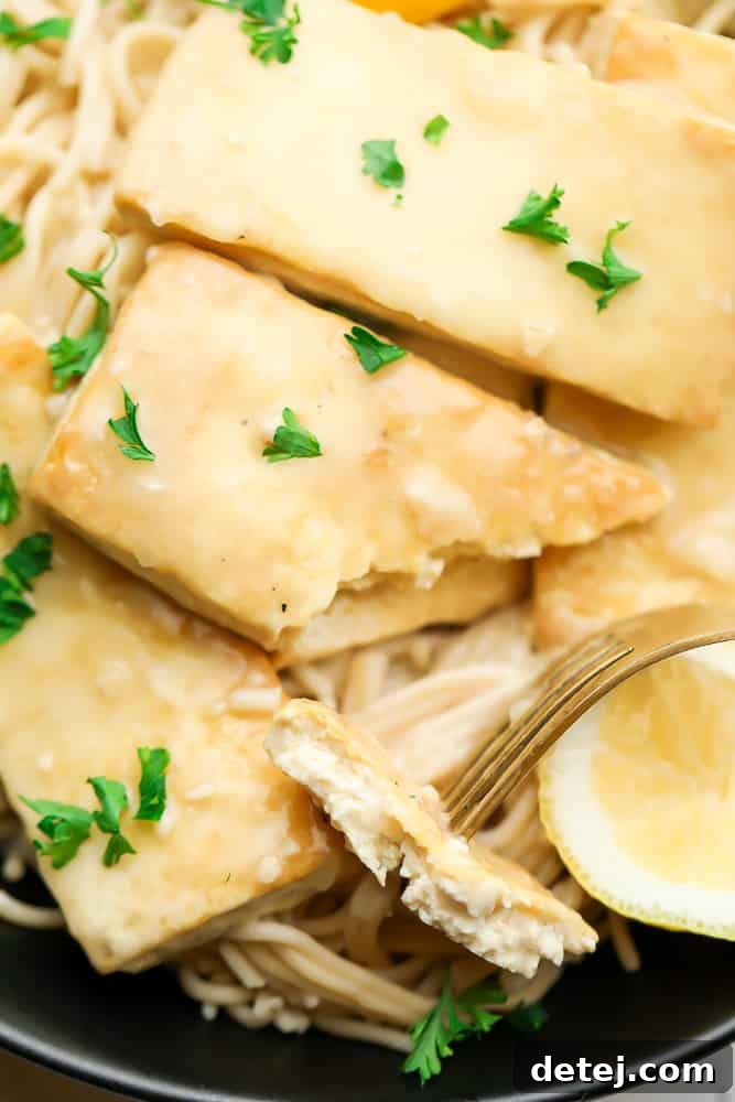A fork piercing a piece of creamy lemon tofu, showing its tender interior.