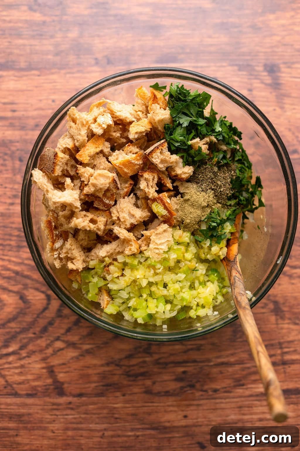 Ultimate Vegan Stuffing 7 Large mixing bowl containing dried bread cubes, chopped celery, and fresh parsley.