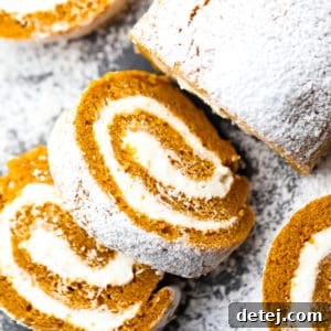 Square image of a perfectly rolled vegan pumpkin cake with white frosting, ready for slicing.
