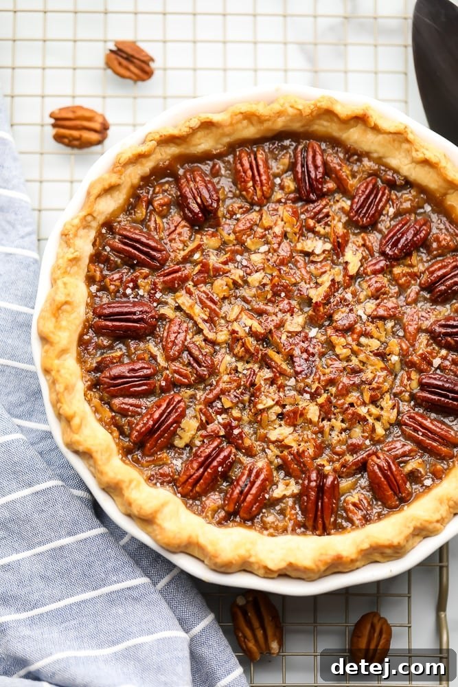 Whole cooked vegan pecan pie on a cooling rack with a blue towel