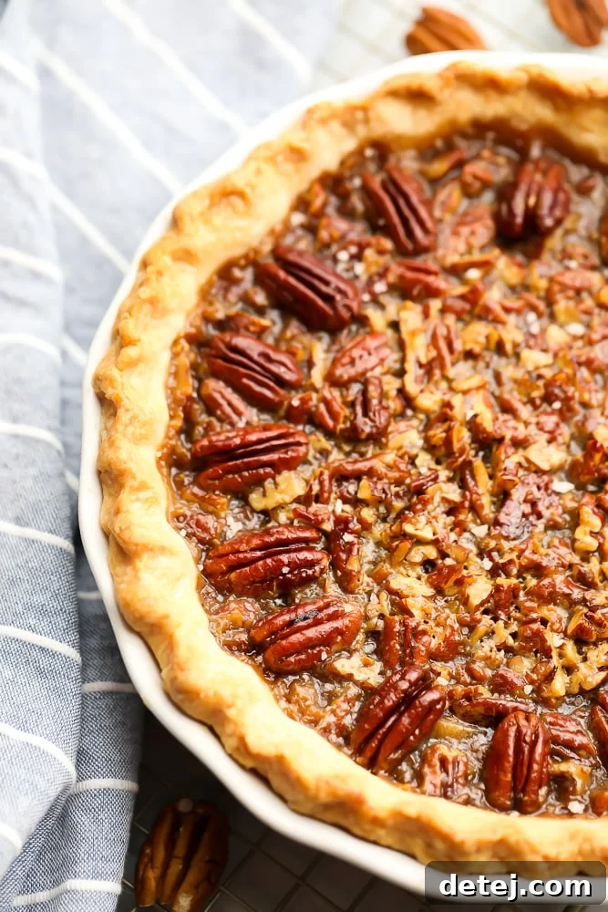 Close up view of a perfectly baked vegan pecan pie, showing the golden crust and glistening pecan topping