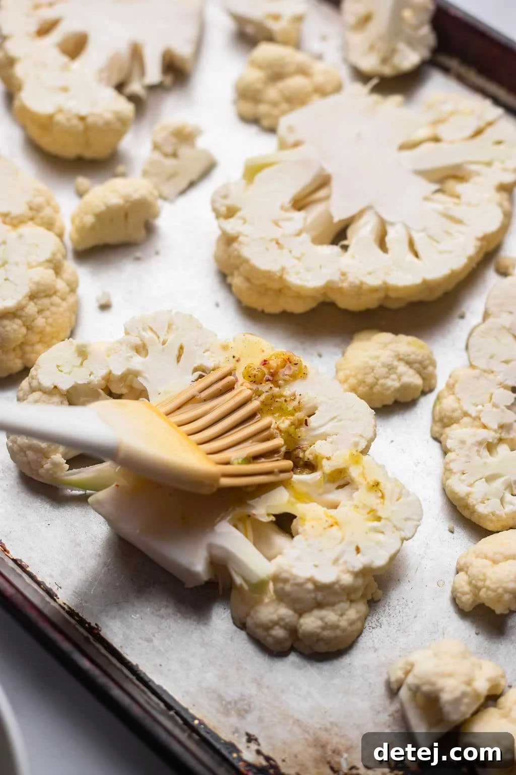 brushing on olive oil garlic mixture onto cauliflower pieces
