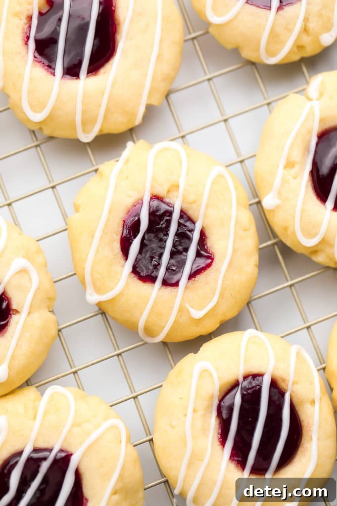 Delicious glazed vegan thumbprint cookies with raspberry jam cooling on a wire rack, ready to be enjoyed.