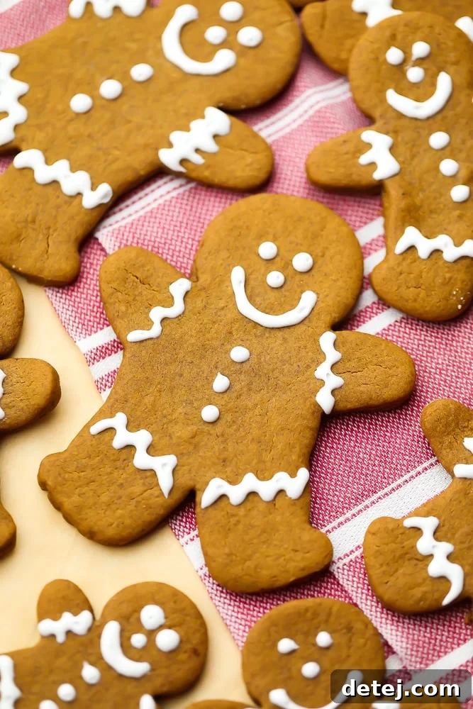 A close-up shot of a single decorated gingerbread cookie person, with more blurred cookies in the background.