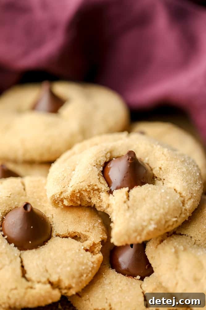 A vegan peanut butter blossom with a bite taken out, revealing the soft cookie texture and the solid chocolate kiss inside.