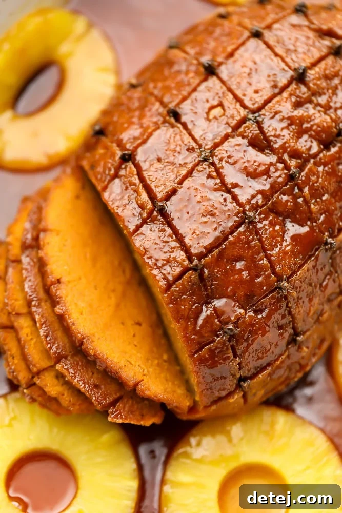 A beautifully sliced vegan ham roast presented in a dish, surrounded by caramelized pineapple rings, showcasing its readiness for a festive meal.