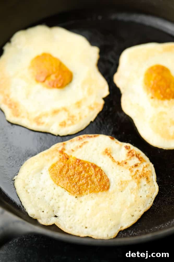 Close up of perfectly cooked vegan eggs in a pan, showing their golden brown edges and realistic texture