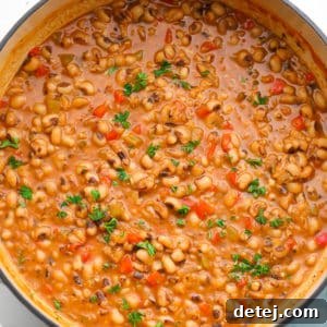 Square image of a pot of creamy black eyed peas with vegetables.