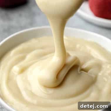 Drizzling vegan custard in a white bowl.