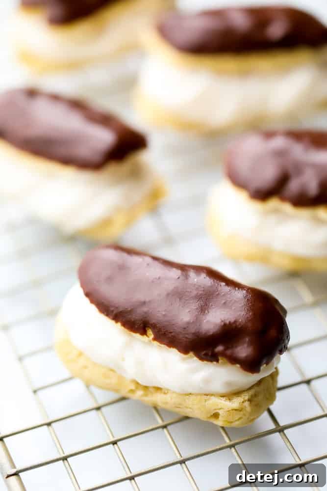 Freshly baked vegan eclairs cooling on a wire rack, showing their golden brown color and classic elongated shape.