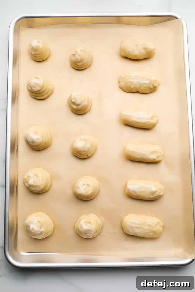 A baking pan filled with uncooked vegan choux pastry mounds, piped and ready for the oven.