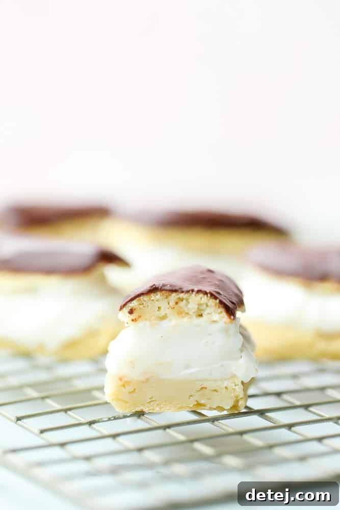 A sliced vegan eclair on a cooling rack, with more eclairs visible in the background, hinting at a delicious spread.