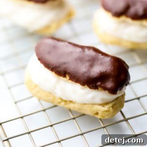 A perfectly square image of a vegan eclair, golden brown and enticing, with more blurred in the background.