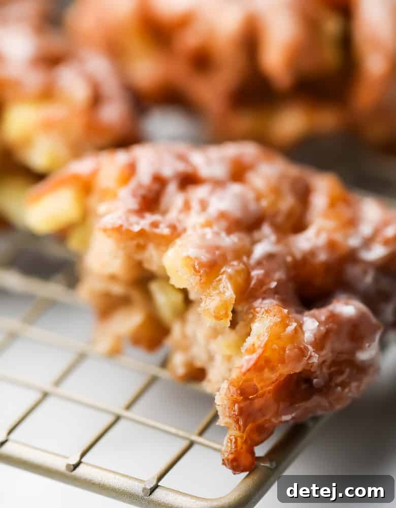 A close-up view of an apple fritter cut in half, revealing the soft, apple-studded interior and crispy exterior.