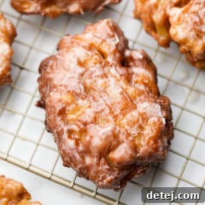 Square image of a golden brown apple fritter on a cooling rack, ready to be glazed.