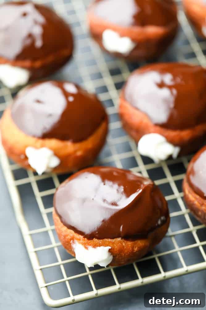 A generous display of cream-filled, chocolate-topped vegan Boston Cream Donuts arranged neatly on a cooling rack, showcasing their irresistible appeal.