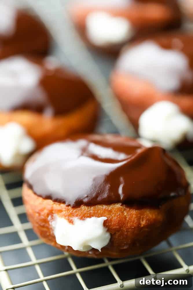 A single vegan Boston Cream Donut resting on a cooling rack, perfectly filled and glazed, ready to be enjoyed.