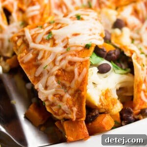 close up of enchilada casserole in white dish, piece being removed