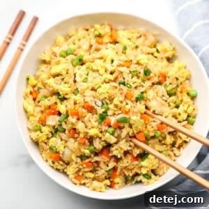 square image of a bowl of rice with veggies in it and chopsticks