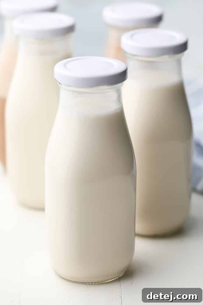 Various glass jars filled with white almond milk, some with chocolate milk in the background