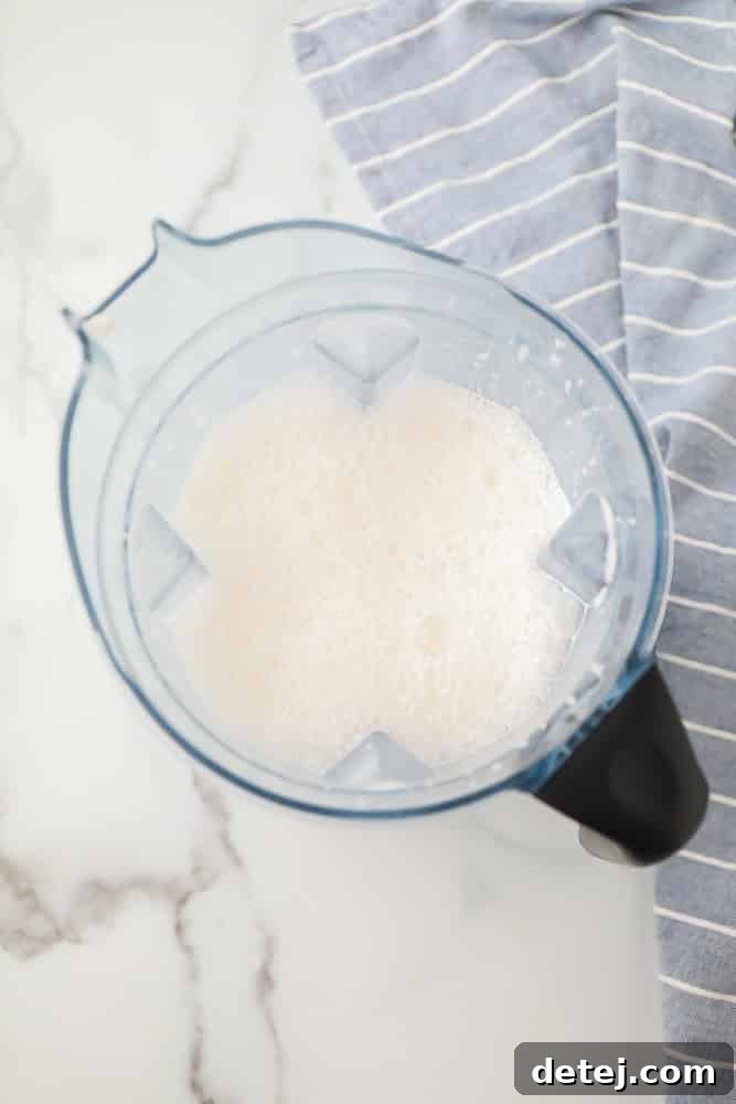 Blender with foamy, creamy white hemp milk from a top-down view