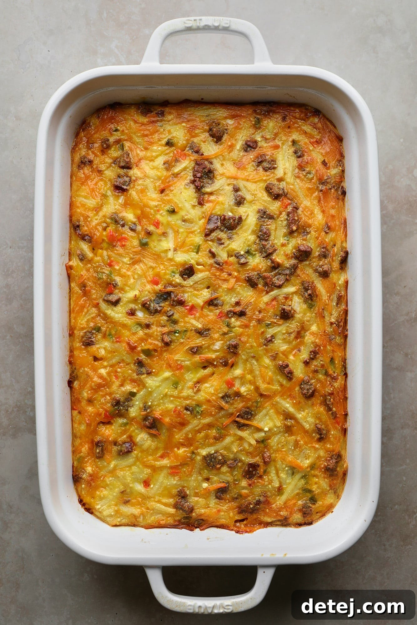 A golden-brown baked vegan breakfast casserole in a white baking dish, fresh out of the oven and perfectly set.