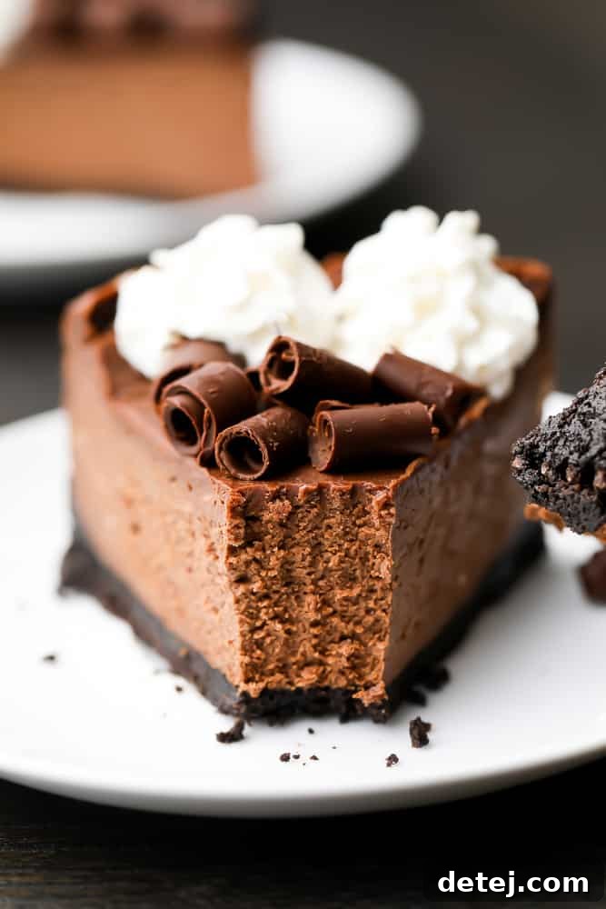Close up of a slice of chocolate cheesecake on a white plate with a bite taken out of it
